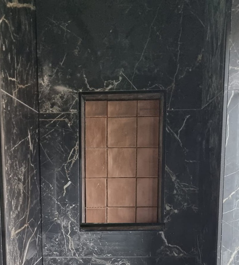Toiletwand in donkere tegels met marmerlook en een ingebouwde nis